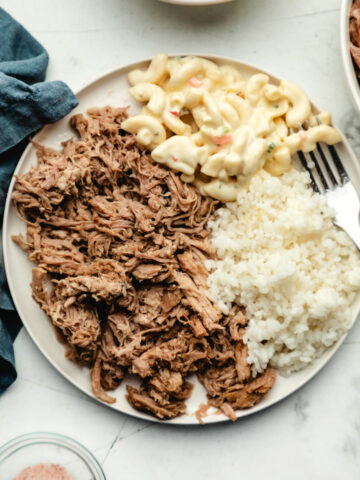 A white plate with Instant Pot kalua pork white rice and macaroni salad on it.