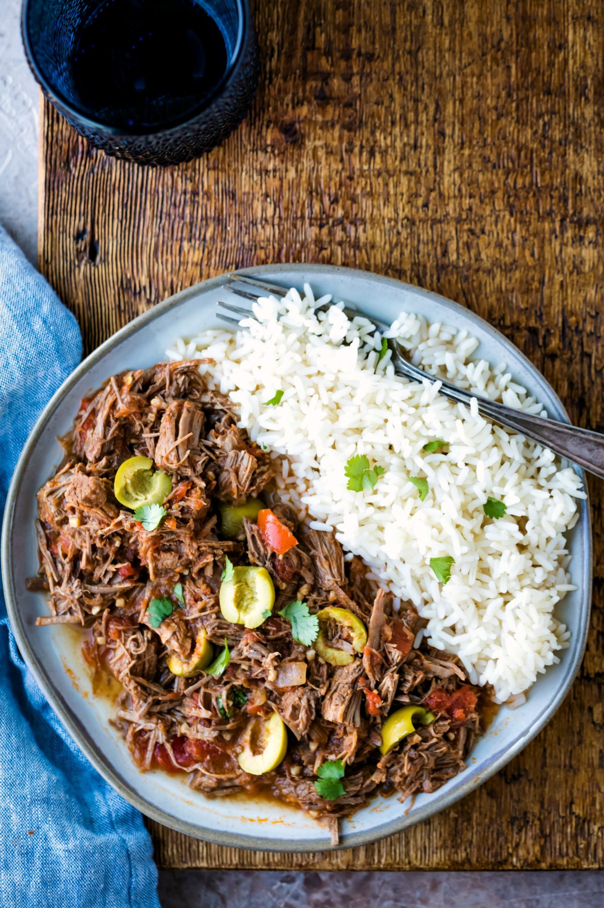 Plate of ropa vieja and rice on a wooden background. 