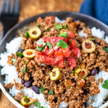 Plate of beef picadillo over black beans and rice.