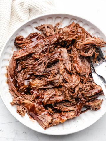 A white dish full of shredded Instant Pot barbecue beef brisket.