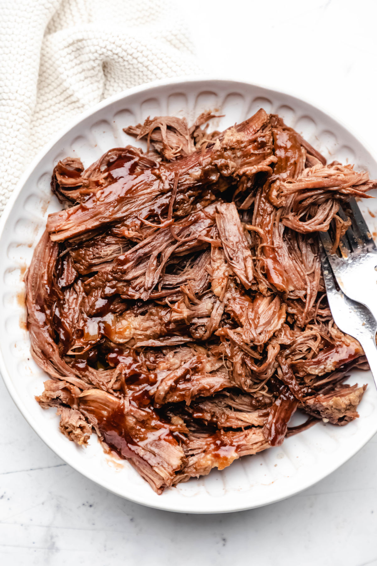 A white dish full of shredded Instant Pot barbecue beef brisket. 