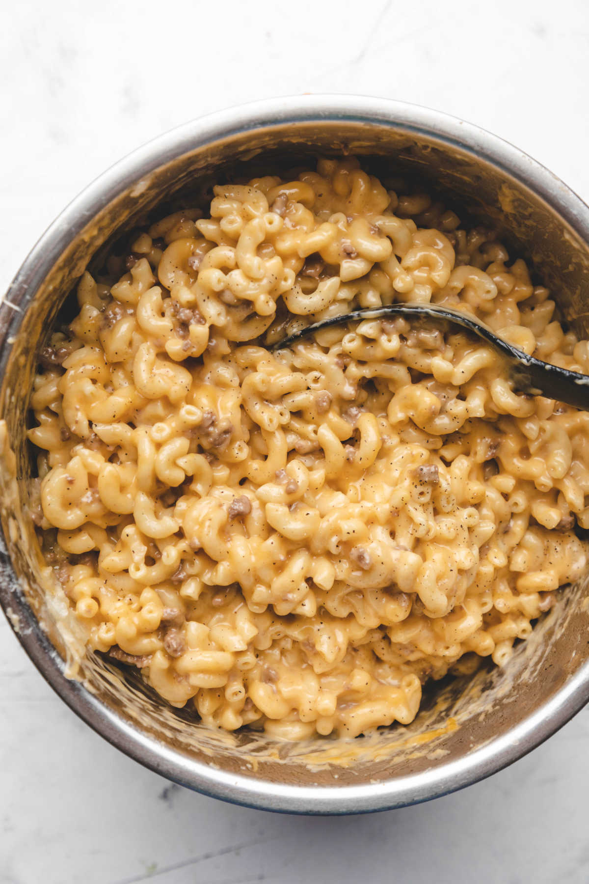 A spoon stirring cheeseburger macaroni in an instant pot. 