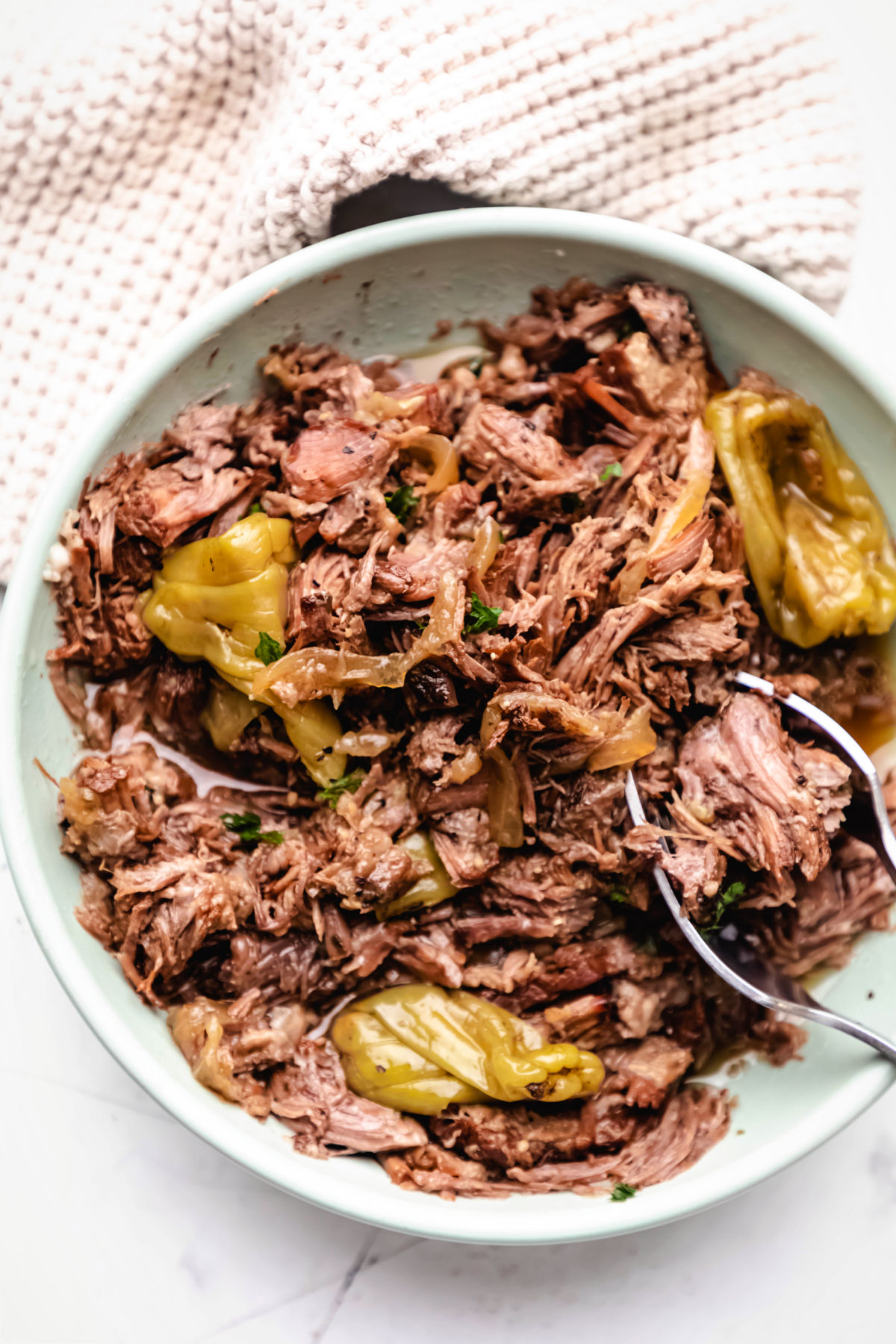 A dish of Instant Pot Mississippi pot roast with three pepperoncinis in it.