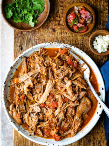 Dish of pork tinga with a meat fork in it.