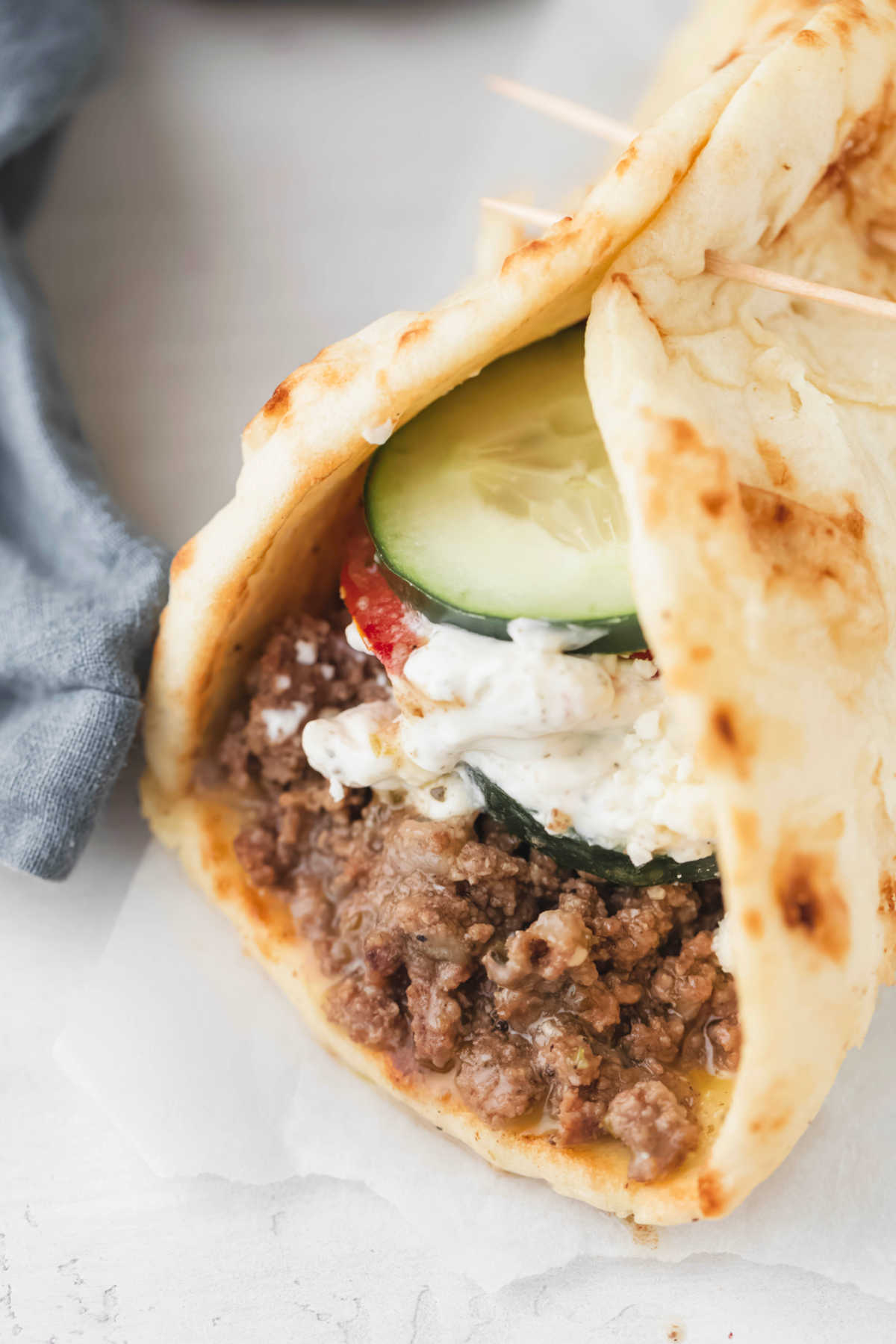 Ground beef gyro topped with tzatziki sauce. 
