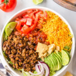 Taco salad in a white dish next to an Instant Pot.