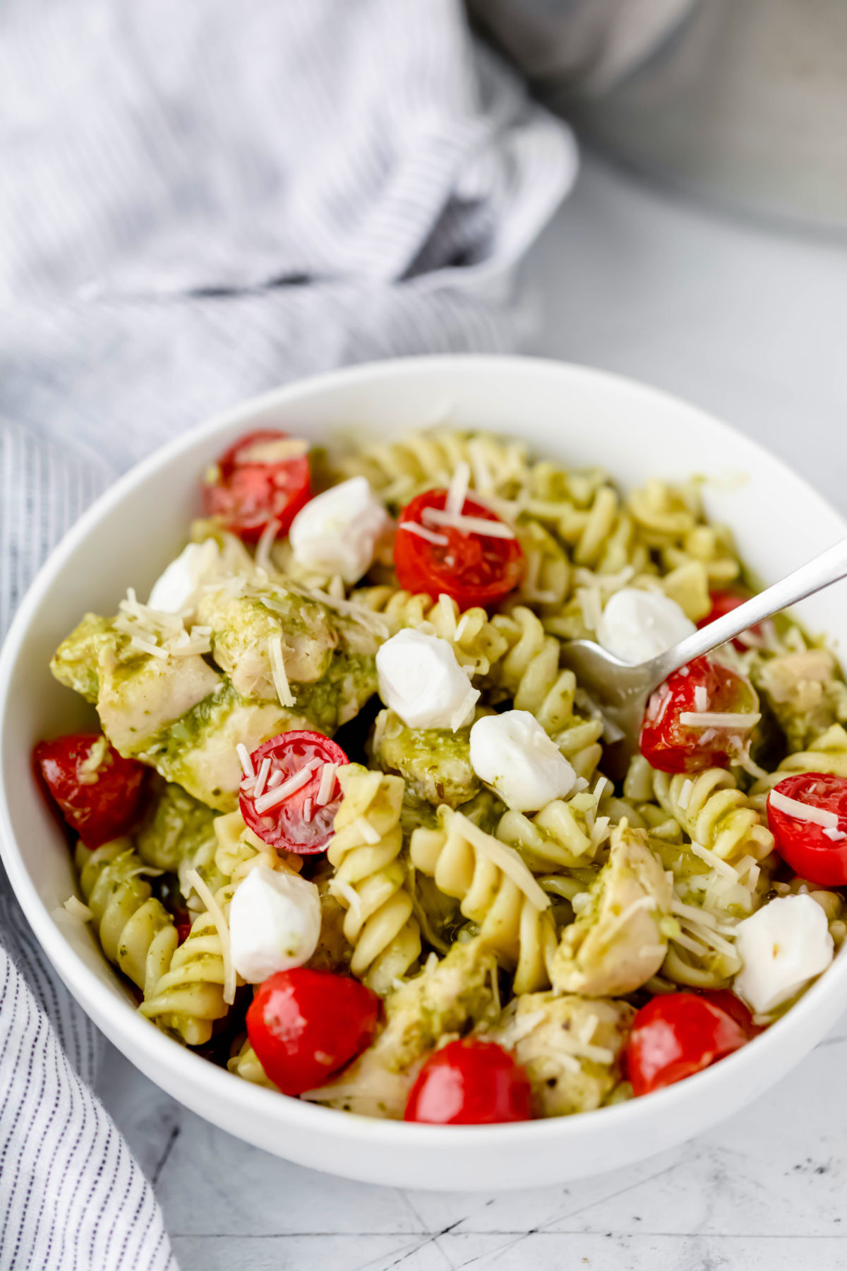 A white dish filled with chicken pesto pasta.
