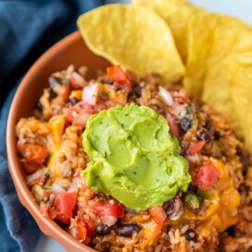 Instant Pot cheesy taco rice in a dish topped with guacamole.