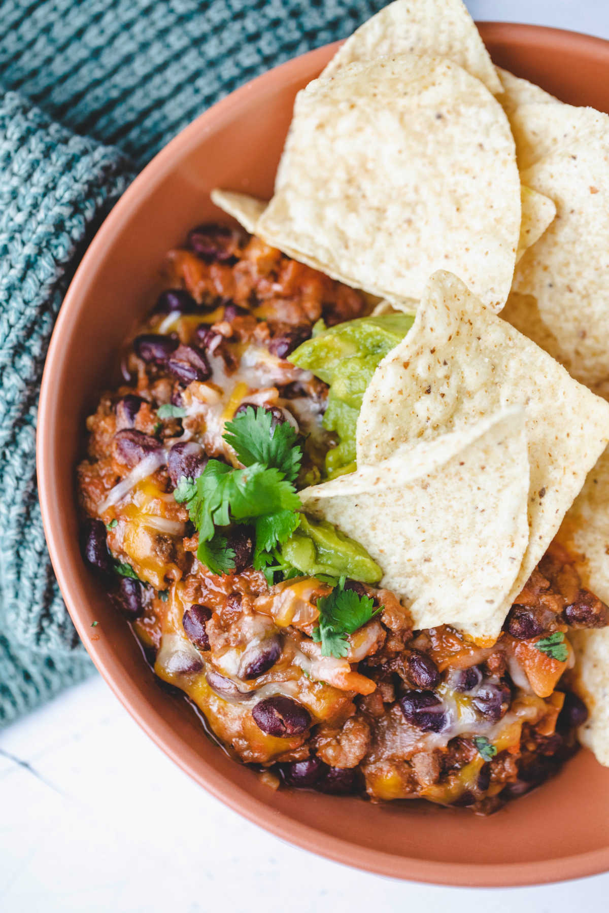 Taco casserole with tortilla chips in a terracotta bowl. 