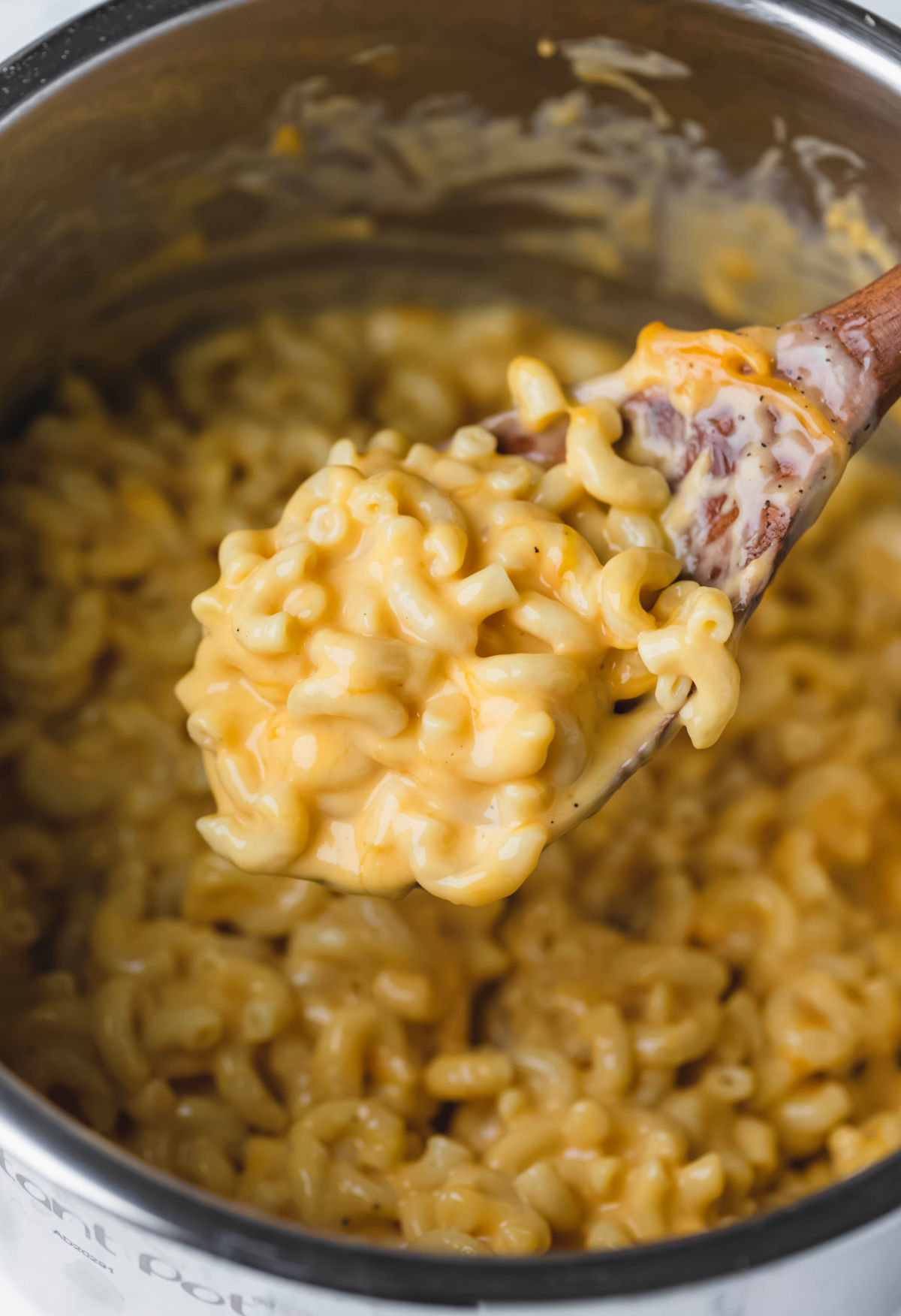 A wooden spoon scooping up macaroni and cheese. 