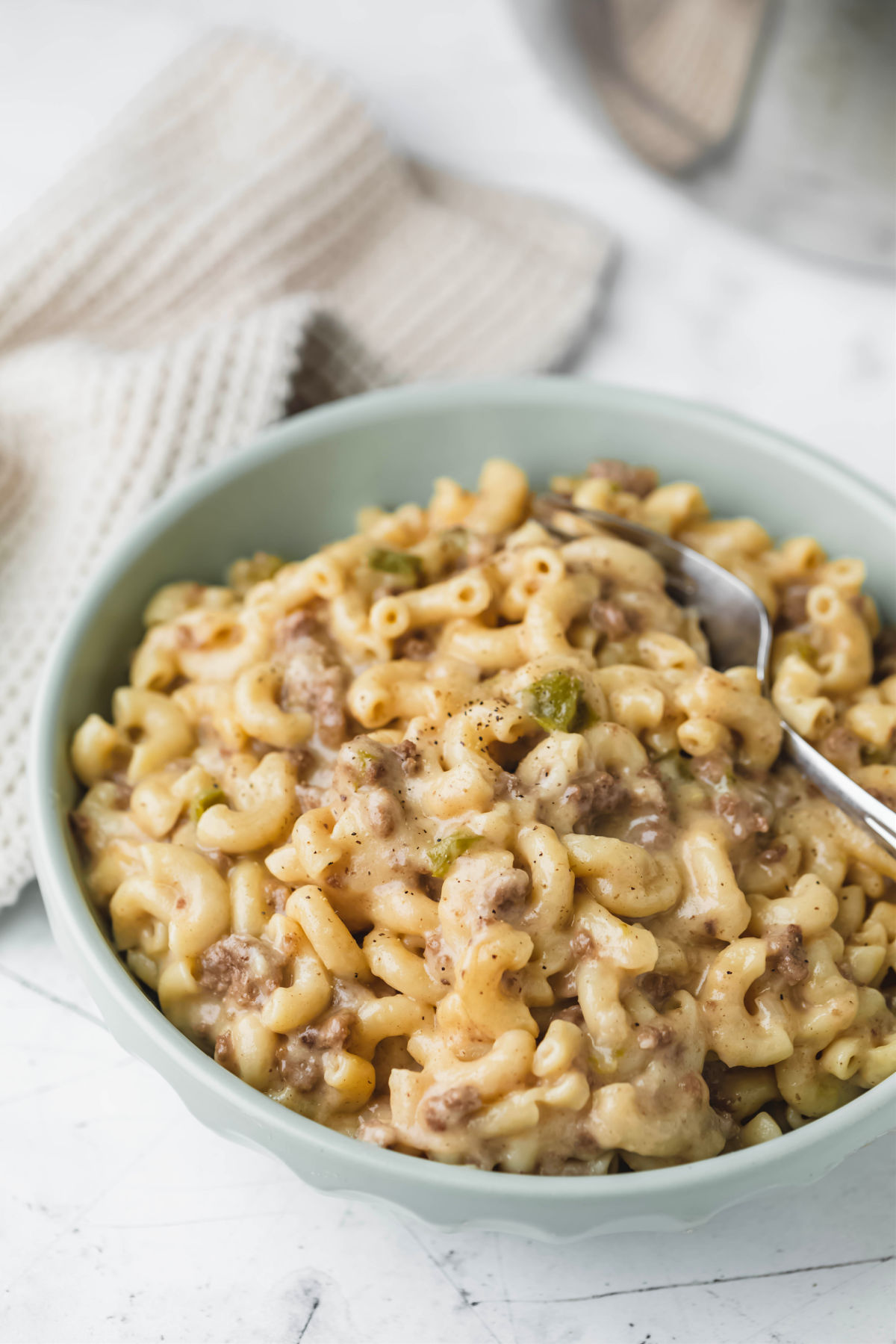 A green dish with Instant Pot Philly cheesesteak pasta and a silver fork in it. 