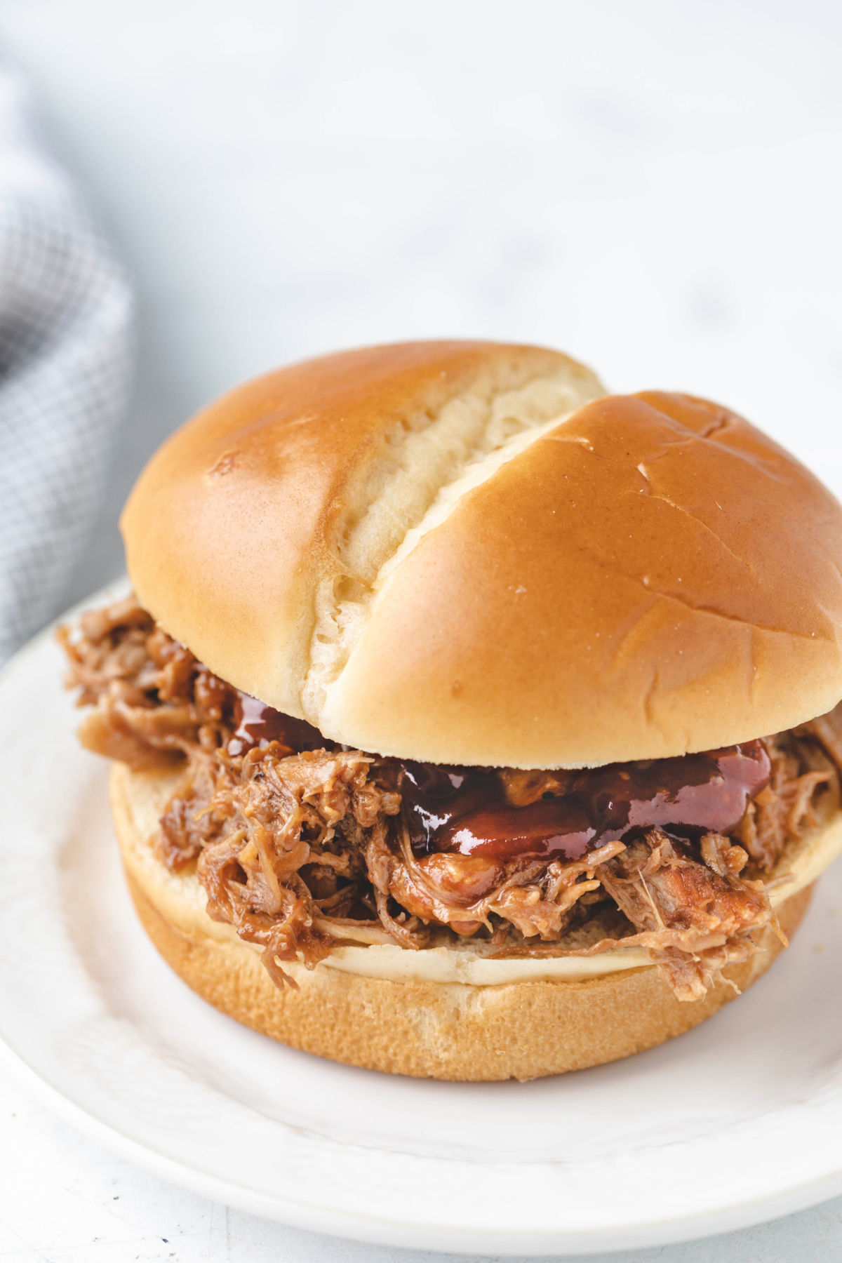 A root beer pulled pork sandwich on a white plate. 