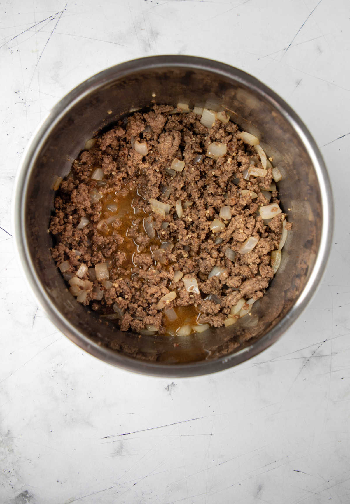 Ground beef onions and beef broth in an instant pot inner pot. 