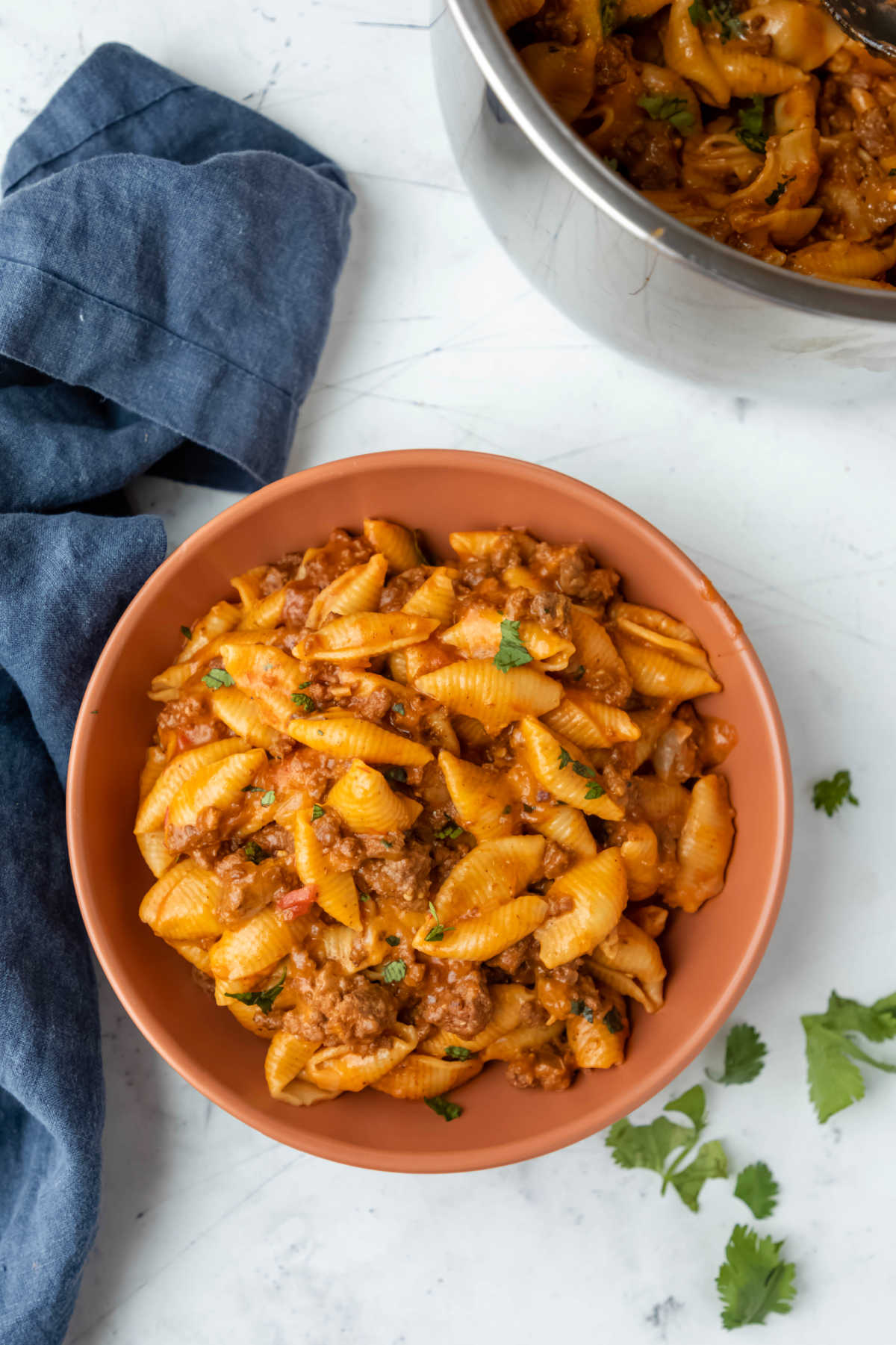 A bowl of taco pasta next to an Instant Pot inner pot. 