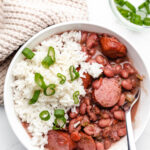 A white bowl of red beans and rice with a silver fork in it.
