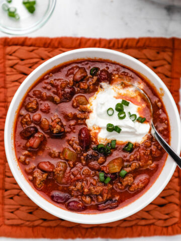A bowl of Instant Pot Wendy's chili topped with sour cream and sliced green onions.
