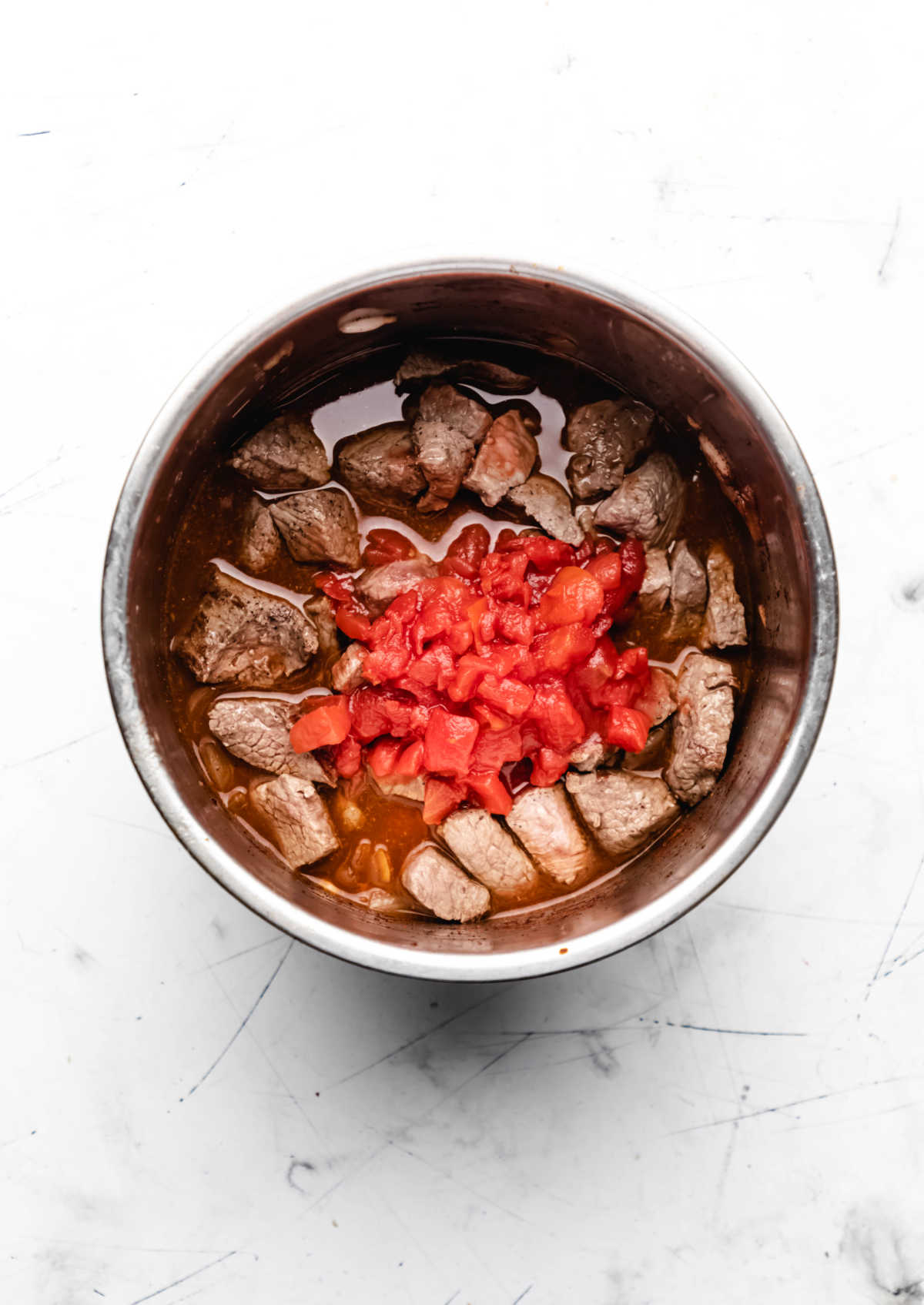 Canned diced tomatoes on stew meat in an instant pot. 
