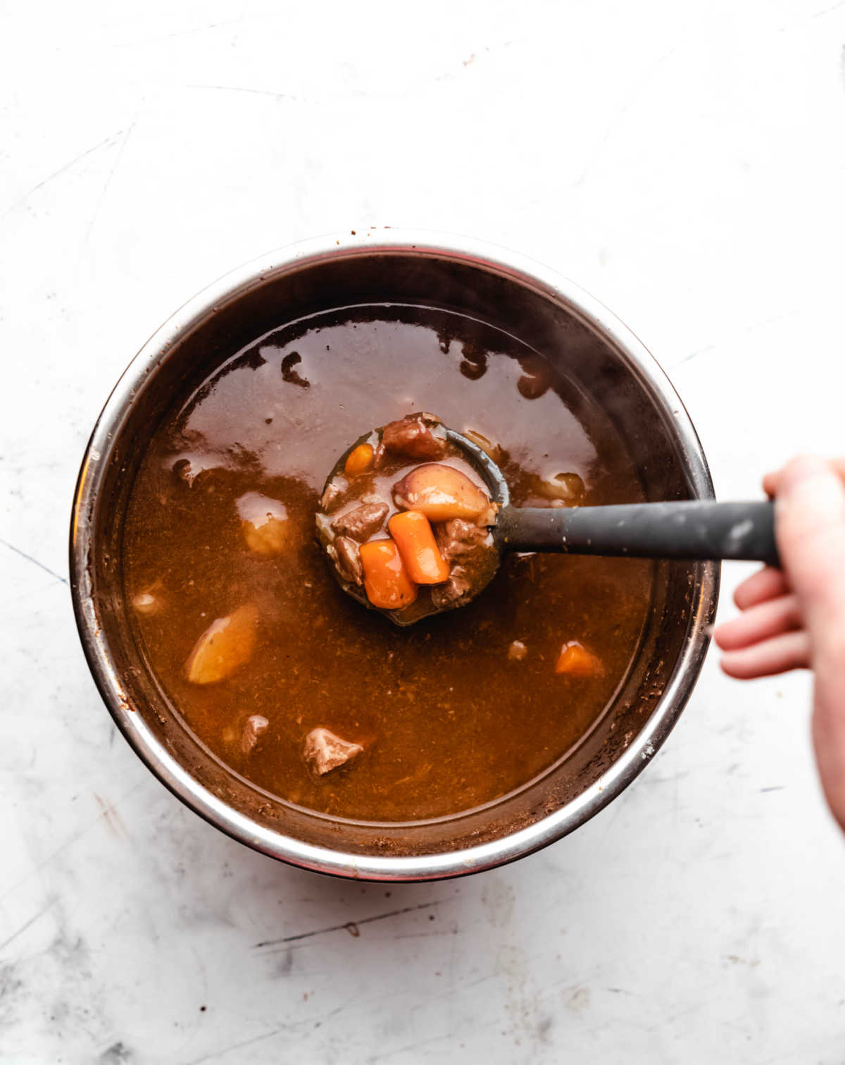 A ladle pulling up a scoop of Instant Pot Guinness beef stew. 