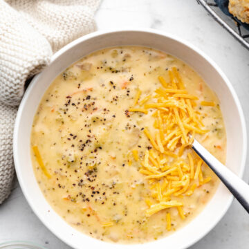 A bowl of Instant Pot broccoli cheddar soup topped with shredded cheddar cheese and black pepper.