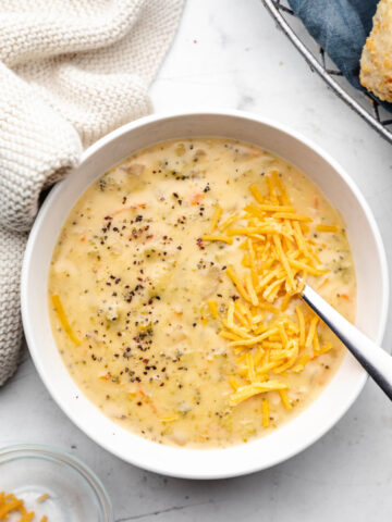 A bowl of Instant Pot broccoli cheddar soup topped with shredded cheddar cheese and black pepper.