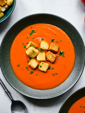 A bowl of Instant Pot tomato soup topped with croutons and parsley.