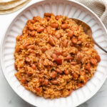 A white plate with Instant Pot Mexican rice and beans with a spoon in it.