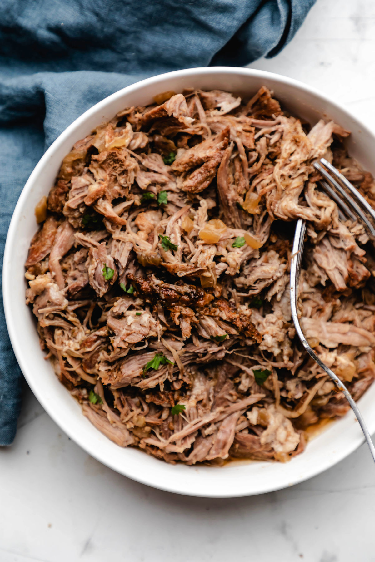 A white dish with Mexican shredded pork and two forks in it.