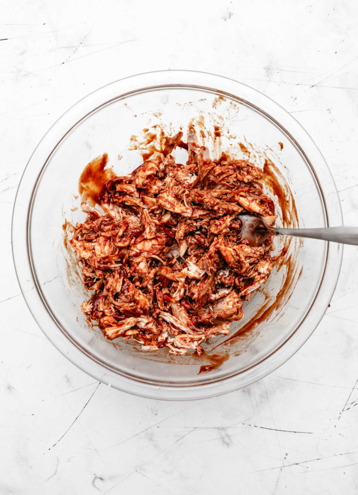 Shredded barbecue chicken in a glass mixing bowl. 