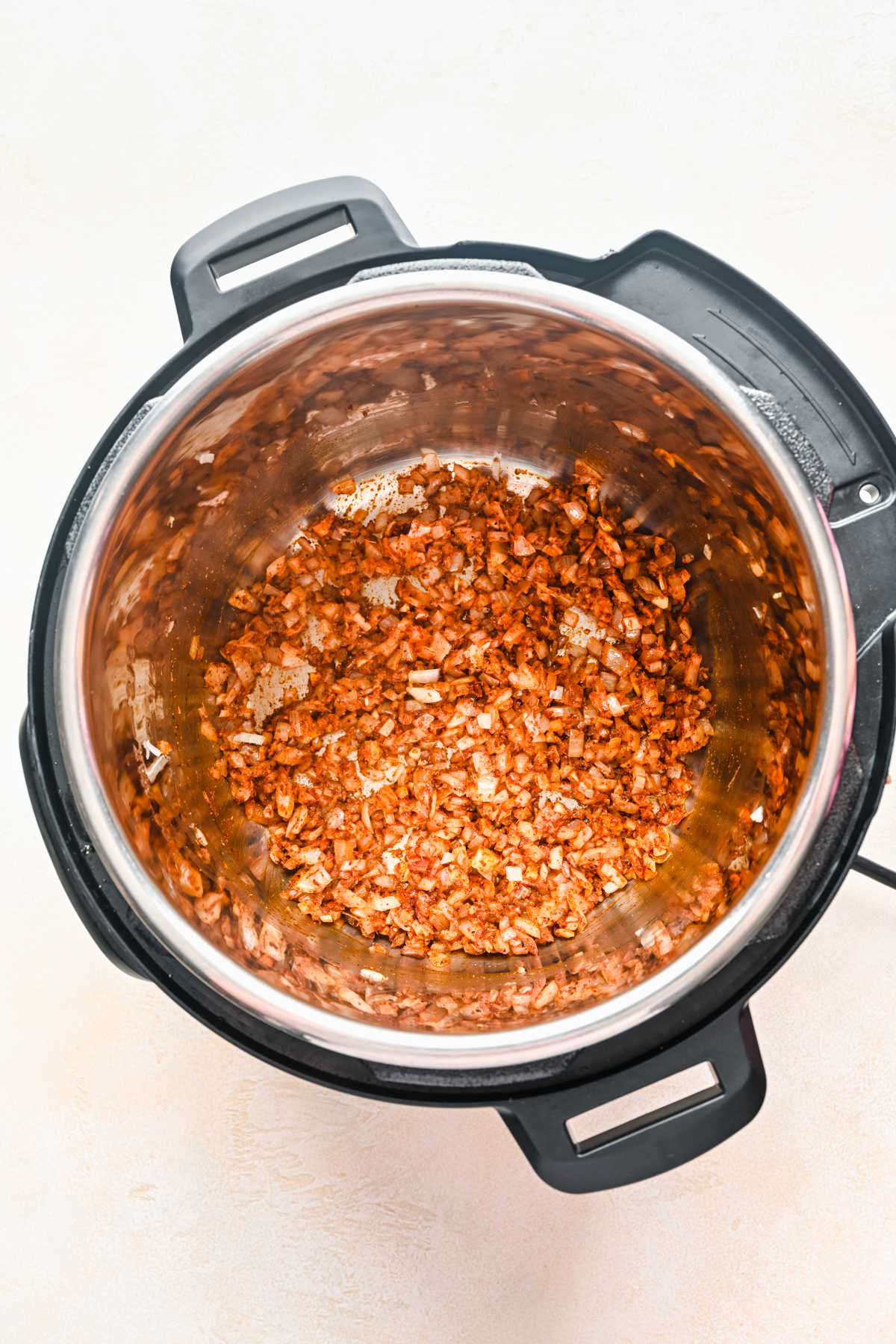Spices and diced onion in an Instant Pot.
