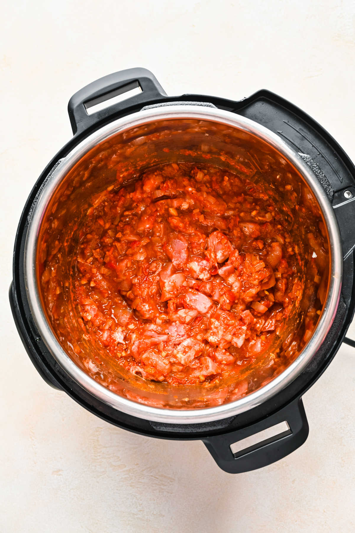 Pieces of chicken in tomato sauce in an instant pot.