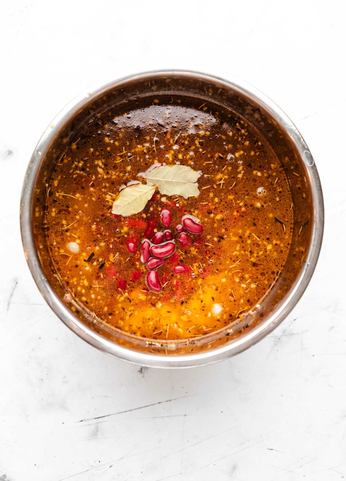 Bay leaves on top of beans in broth.