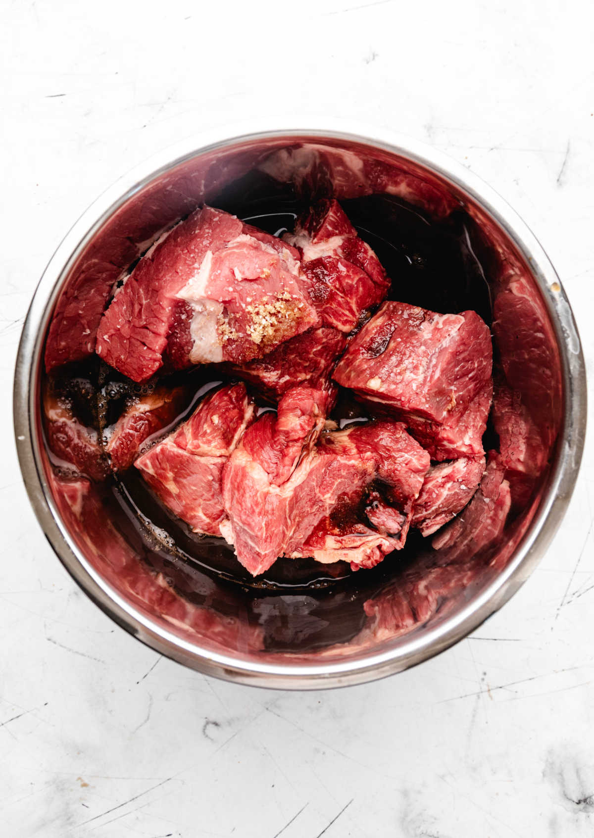 Vinegar mixture poured over pieces of chuck roast in an Instant Pot. 