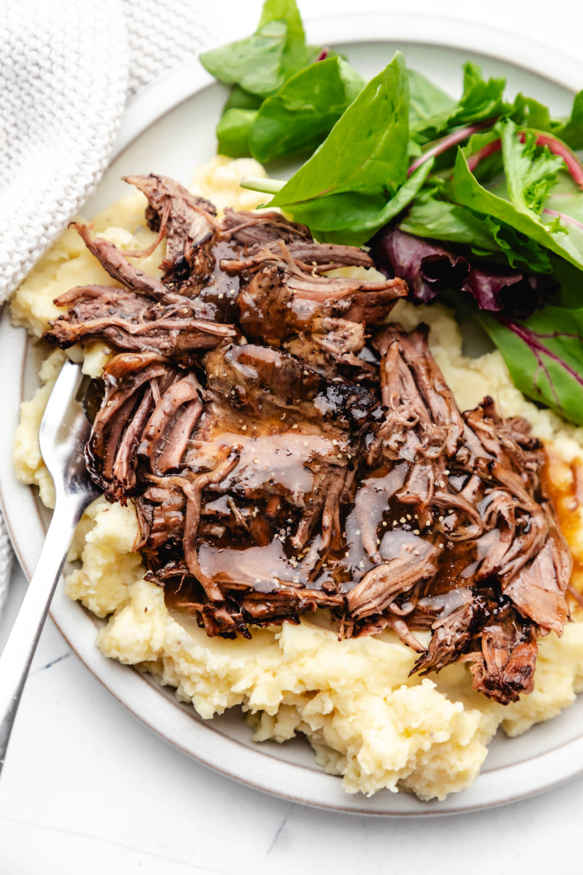 Instant pot balsamic beef on a white plate over mashed potatoes. 