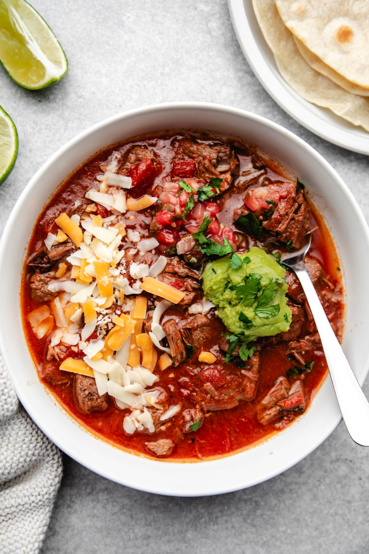 A bowl of Instant Pot beef enchilada soup with a silver spoon in it. 