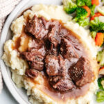 Instant Pot beef tips with gravy on top of a bed of mashed potatoes.