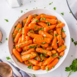 A white dish of Instant Pot glazed carrots topped with parsley.