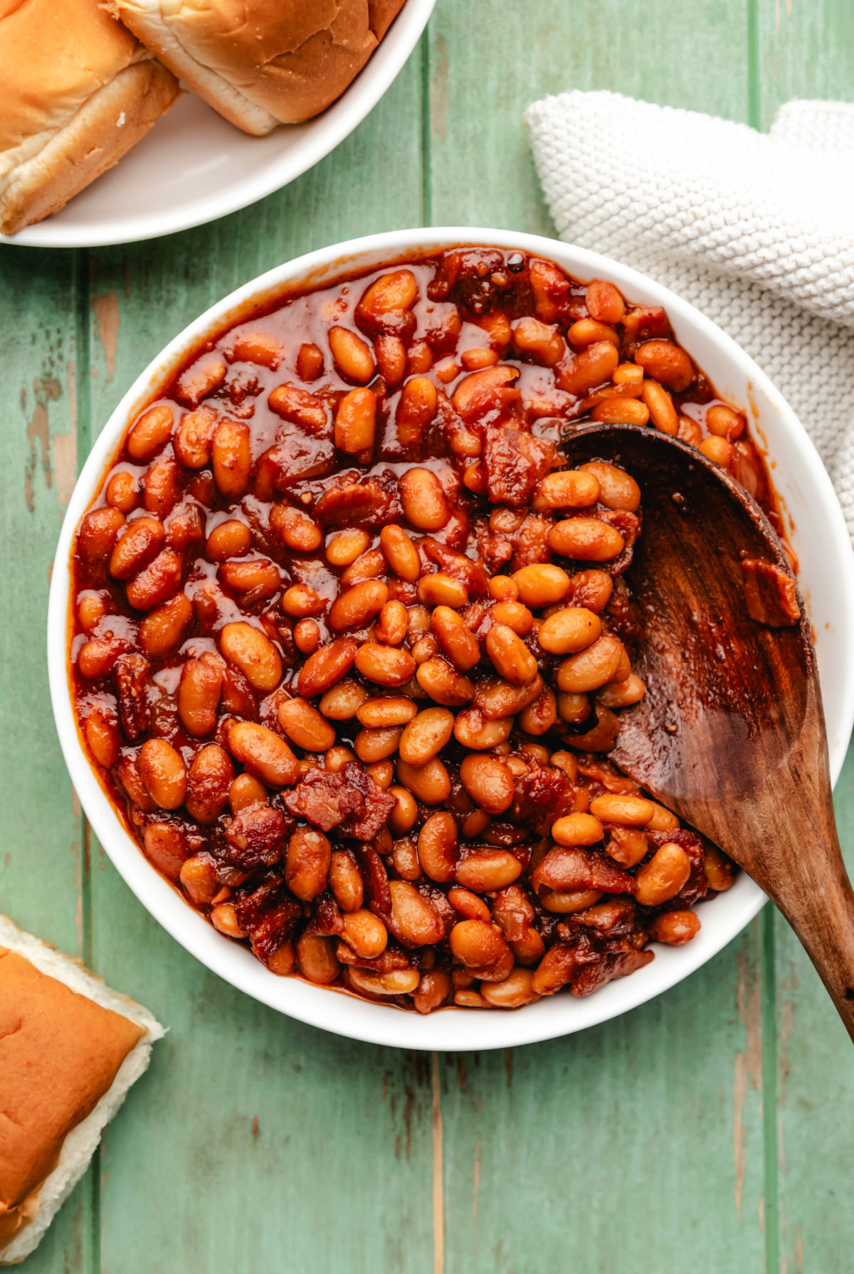A bowl of Instant Pot baked beans next to a cream kitchen linen.