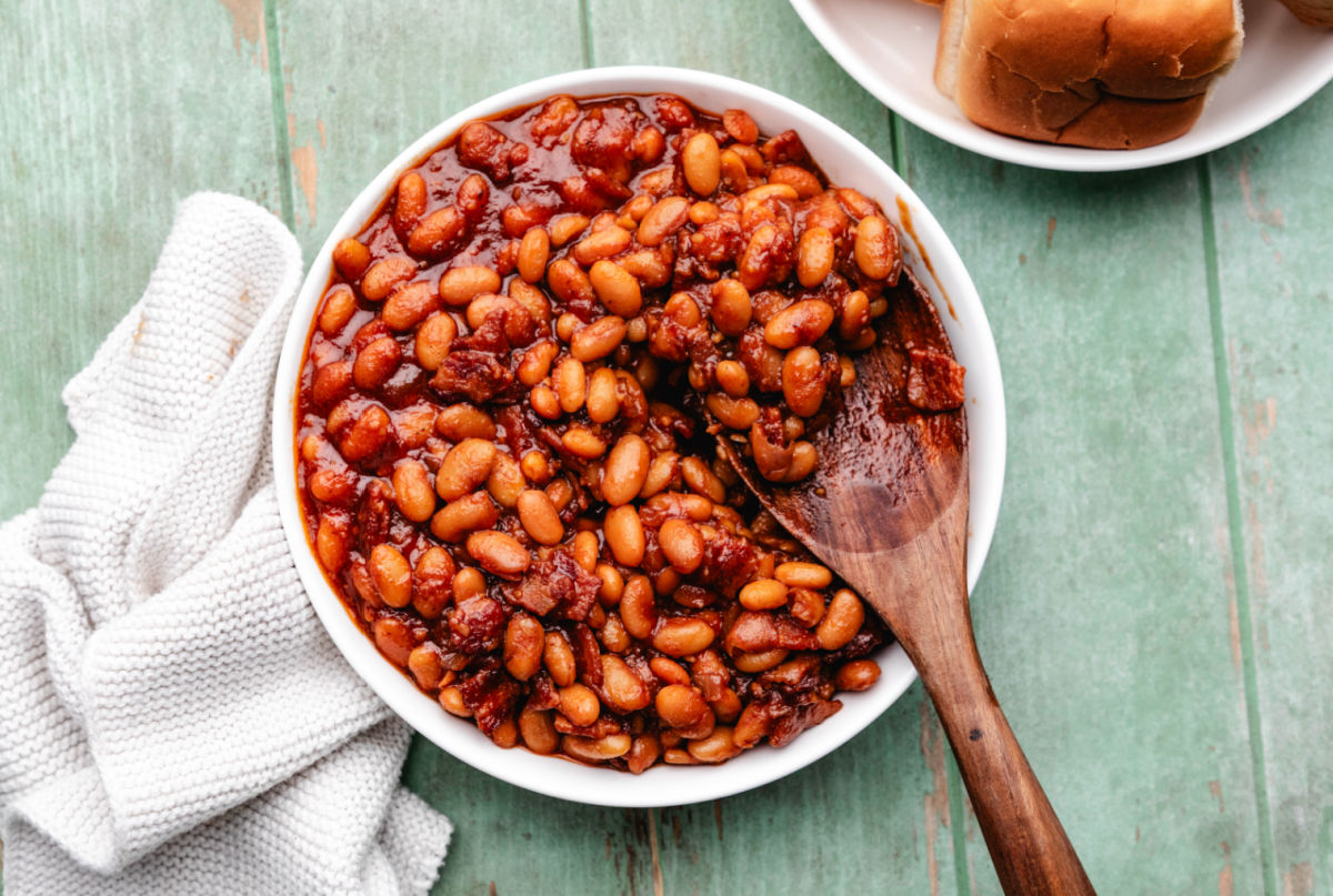 A bowl of Instant Pot baked beans with a wooden spoon in it.