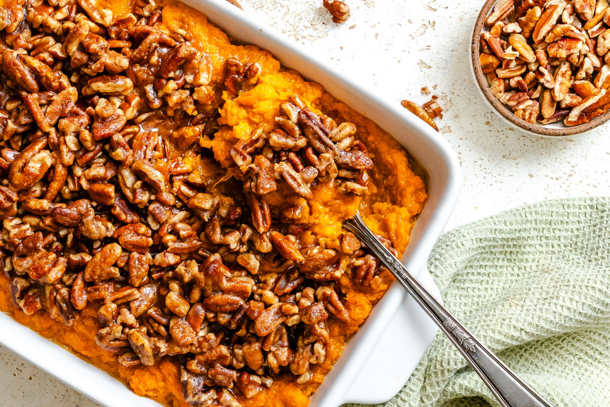 A dish of Instant Pot sweet potato casserole next to a dish of pecans.